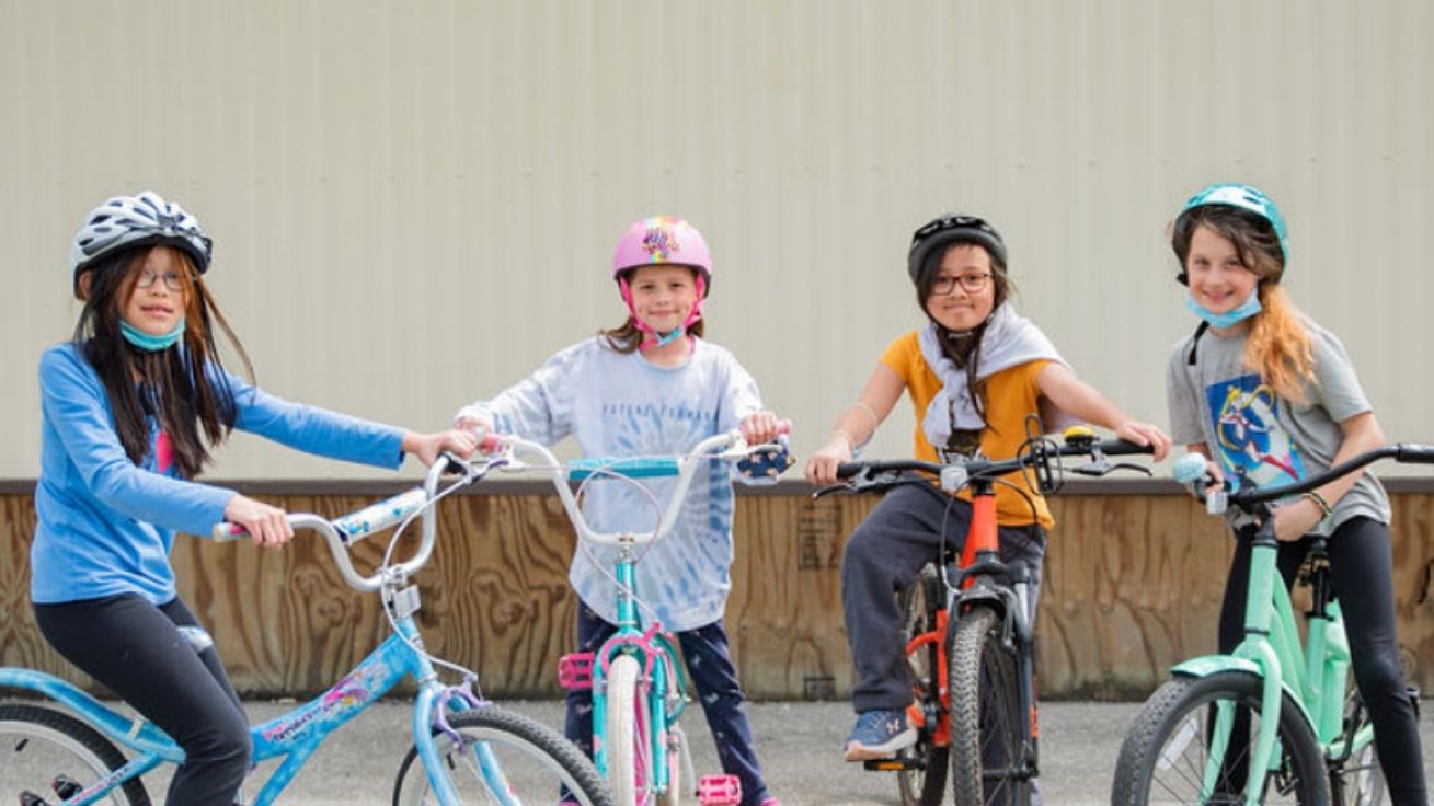 4 children with helmets on their bikes